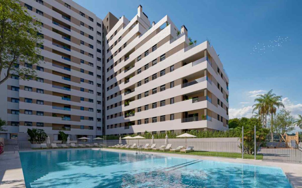 Fachada del edificio junto con una piscina de obra nueva de la promoción de viviendas Célere Nervión en Sevilla capital.