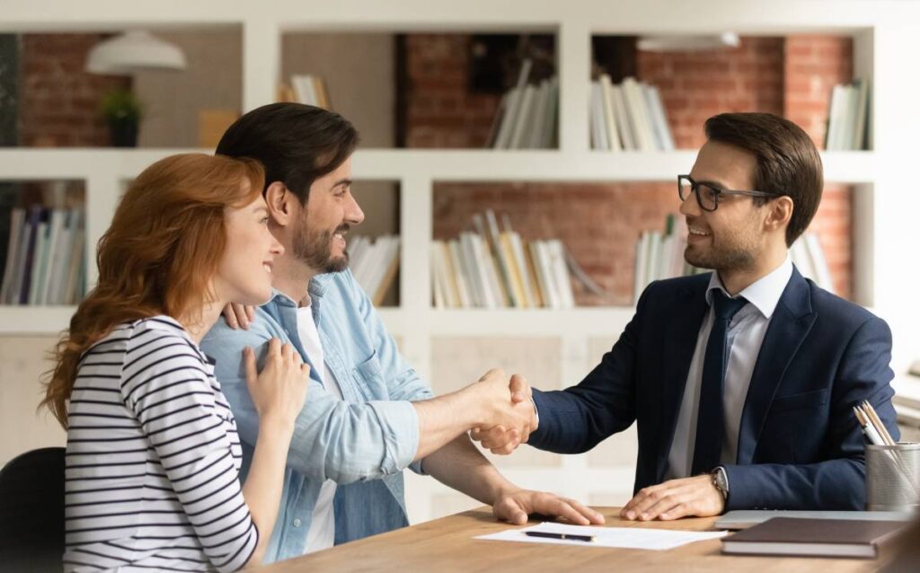 Una pareja haciendo un acuerdo con un agente del banco sobre la hipoteca de vivienda.
