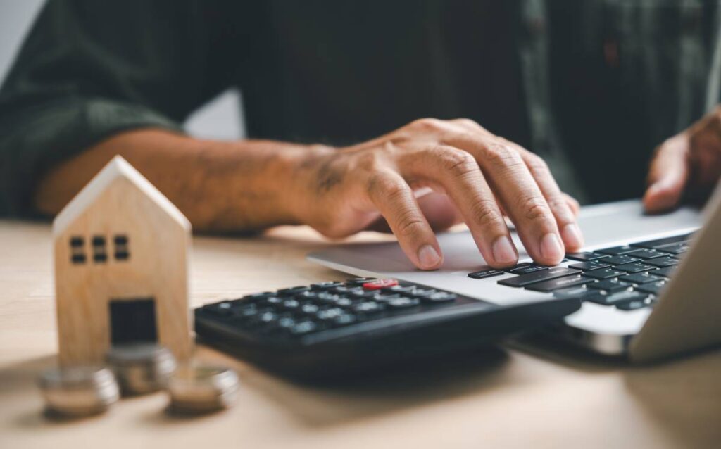 Manos de un hombre joven en un ordenador calculando el euríbor para la hipoteca de una vivienda. 