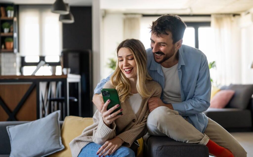 Pareja sonriendo y mirando el móvil
