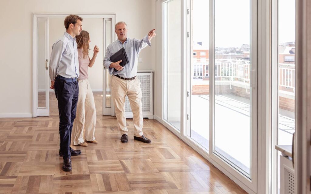 Agente inmobiliario mostrando un piso vacío a una pareja joven