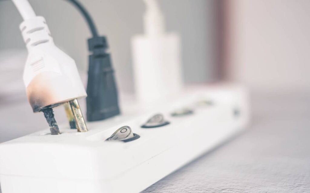 Enchufe blanco con marcas de quemaduras por un cortocircuito eléctrico