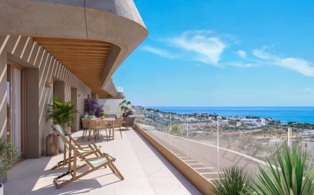 Amplia terraza de diseño moderno con suelo de baldosas claras, dos tumbonas de madera y tela de rayas en primer plano, y una mesa de comedor de ratán con sillas al fondo