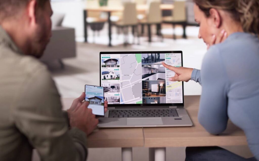 Pareja buscando casas en un ordenador y teléfono móvil