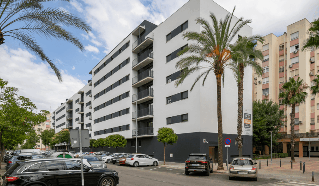 Exterior de un moderno edificio de apartamentos residencial de obra nueva en Sevilla Este con palmeras y coches aparcados en la calle