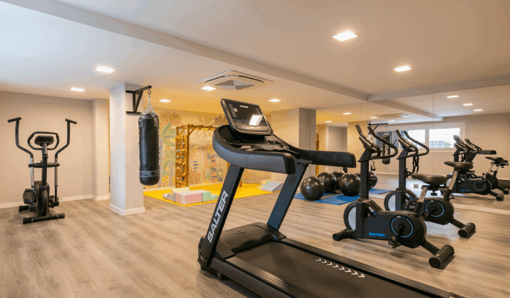 Gimnasio comunitario equipado con cinta de correr, bicicletas estáticas, saco de boxeo y zona de estiramientos en Célere LAOS