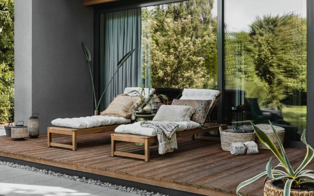 Tumbonas de madera con cojines blancos en una terraza moderna con suelo de madera