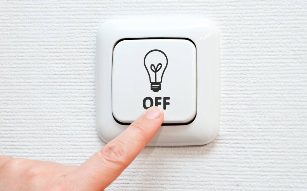 Dedo pulsando un interruptor en posición "OFF" para reducir los gastos fijos del hogar