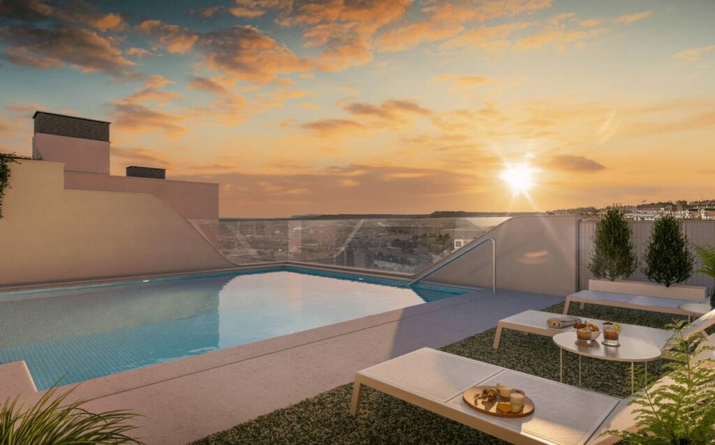Piscina exterior con solárium en la última planta de la promoción Célere Parqueluz III al atardecer