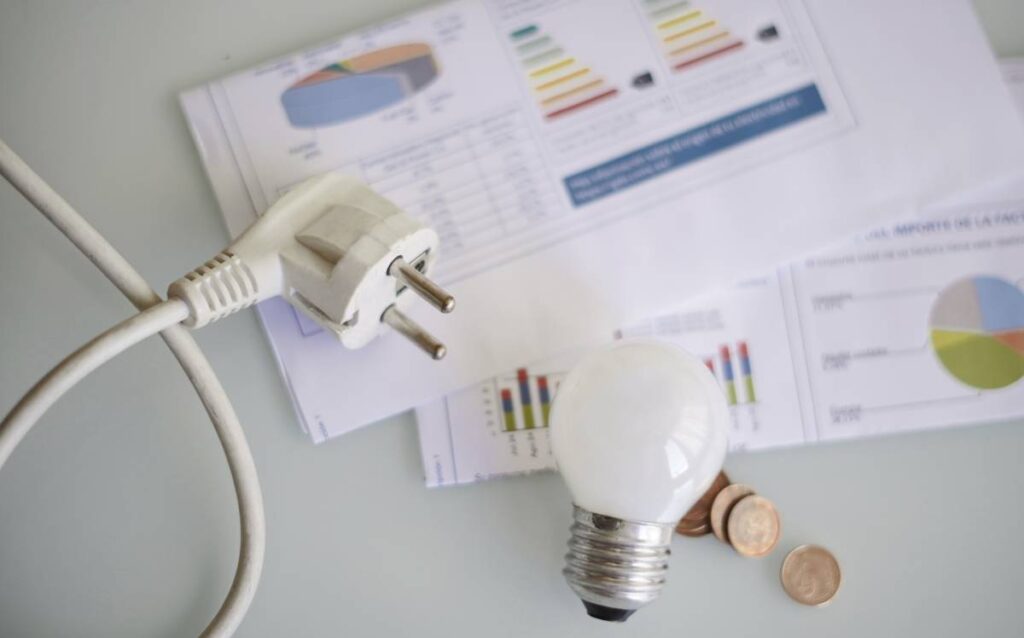 Factura de la luz con bombilla, enchufe y monedas para ahorrar