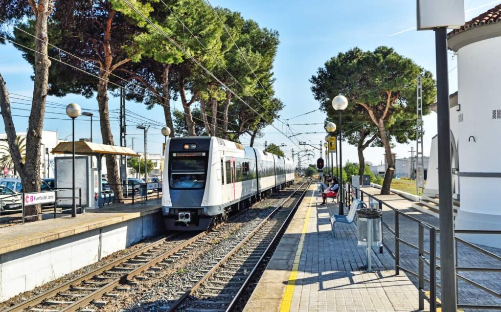 Estación de metro de Paterna con un tren llegando al andén rodeado de árboles