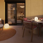 Terraza de una vivienda de obra nueva Vía Célere Jara, equipada con zona de comedor exterior, sillón de descanso, iluminación ambiental y acceso directo al salón mediante puertas acristaladas.