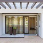 Entrada principal de Célere Arce con acceso al edificio residencial, diseño contemporáneo, acabados modernos, zonas ajardinadas decorativas y espacios comunes acondicionados.