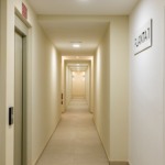 Pasillo interior de Célere Arce con acceso a viviendas, ascensores, iluminación moderna y zonas comunes.