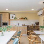 Sala social de Célere Arce con cocina equipada, mesas para reuniones, zona de comedor y espacios comunes diseñados para el ocio, la convivencia y el disfrute de los residentes.