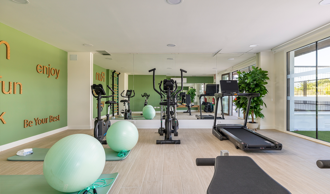 Gimnasio de Célere Arce con cintas de correr, bicicletas elípticas, zona de entrenamiento funcional, espejos de gran formato, balones de fitness y amplios espacios.