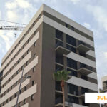 La imagen muestra el avance de las obras de Célere Acacia II en julio de 2026, con varios edificios residenciales prácticamente terminados, fachadas acabadas en tonos claros y oscuros, amplias terrazas, carpinterías instaladas y una grúa torre.