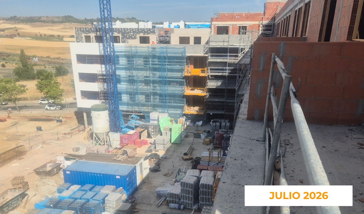 La imagen muestra el avance de las obras de una promoción de Vía Célere en julio de 2026, con varios edificios en construcción, andamios en las fachadas, una grúa torre y materiales de obra distribuidos por el recinto.