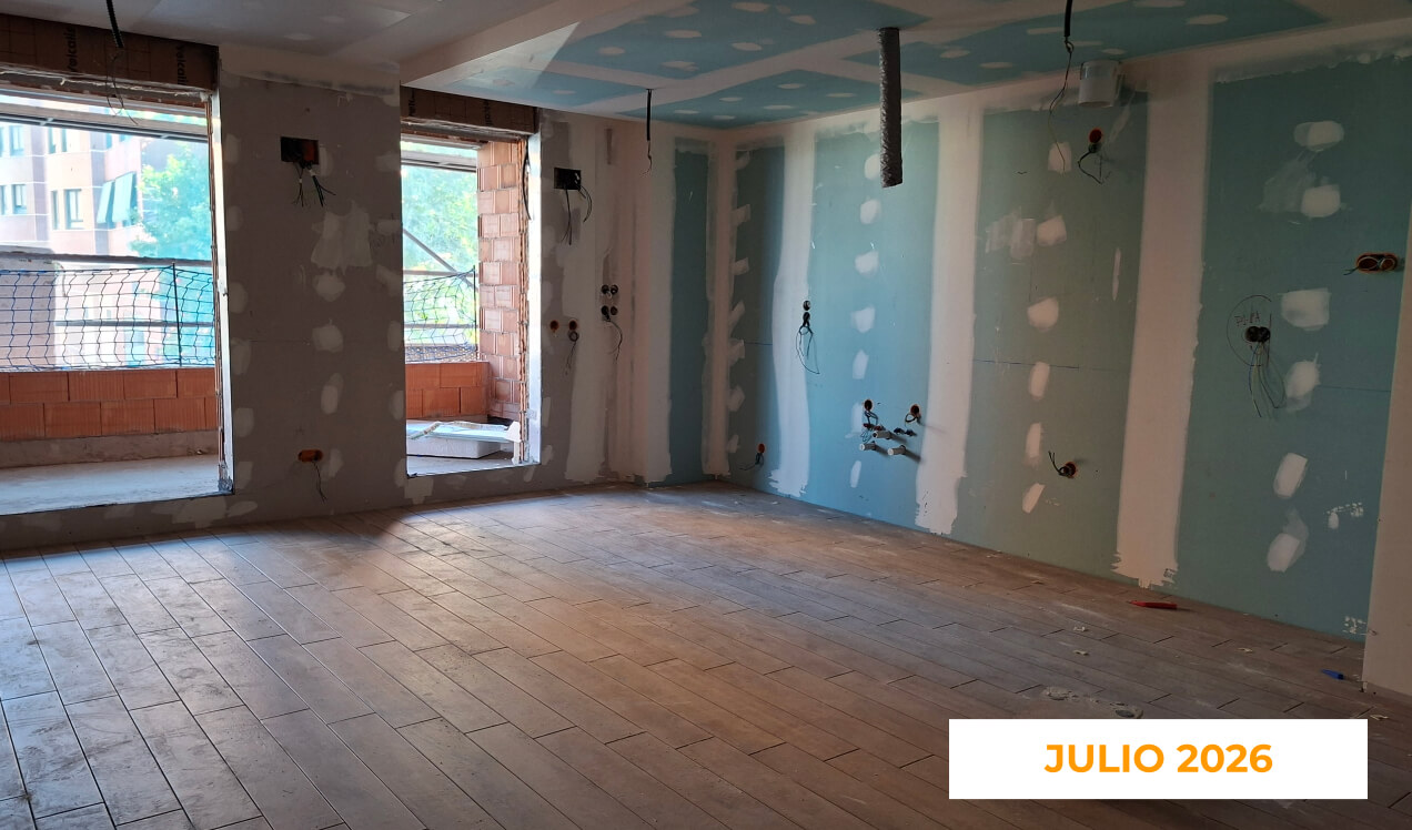 La imagen muestra una vivienda en construcción de la promoción Célere Parqueluz III en julio de 2026, con el solado ya instalado, tabiques de yeso laminado en fase de acabado, instalaciones vistas y acceso a una terraza a través de grandes ventanales.