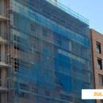 La imagen muestra el avance de las obras de Célere Parqueluz III en julio de 2026, con una fachada residencial en fase de ejecución, andamios cubiertos con malla de protección, estructura de hormigón visible y trabajos de cerramiento exterior en desarrollo.