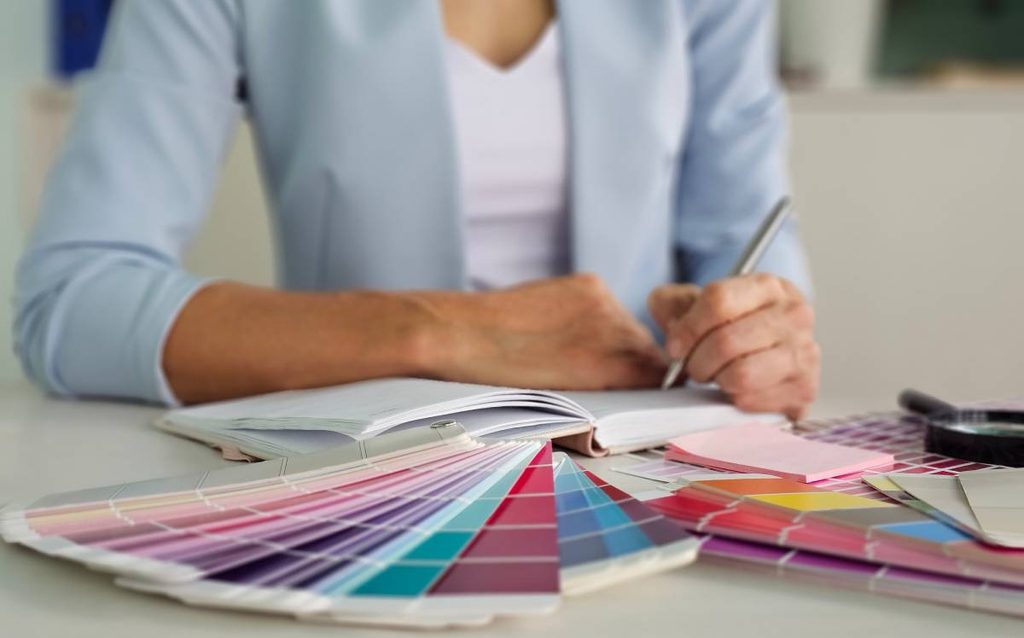Persona seleccionando colores con muestras de pintura para combinar tonos en la decoración del hogar