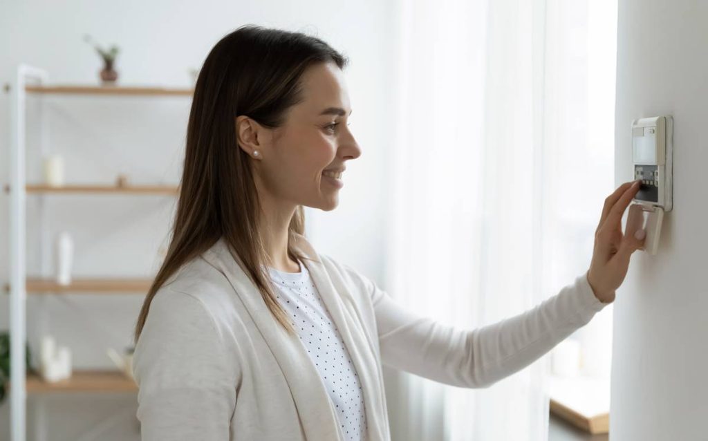 Mujer ajustando el termostato de su vivienda para mejorar la eficiencia energética y reducir el consumo eléctrico en el hogar