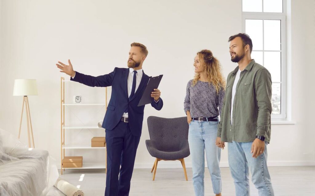 Agente inmobiliario mostrando una vivienda a una pareja interesada en comprar una casa y solicitar una hipoteca