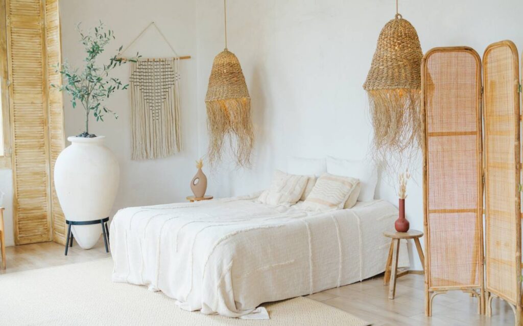 Dormitorio decorado con fibras naturales, lámparas colgantes de mimbre, biombo de ratán y textiles en tonos neutros