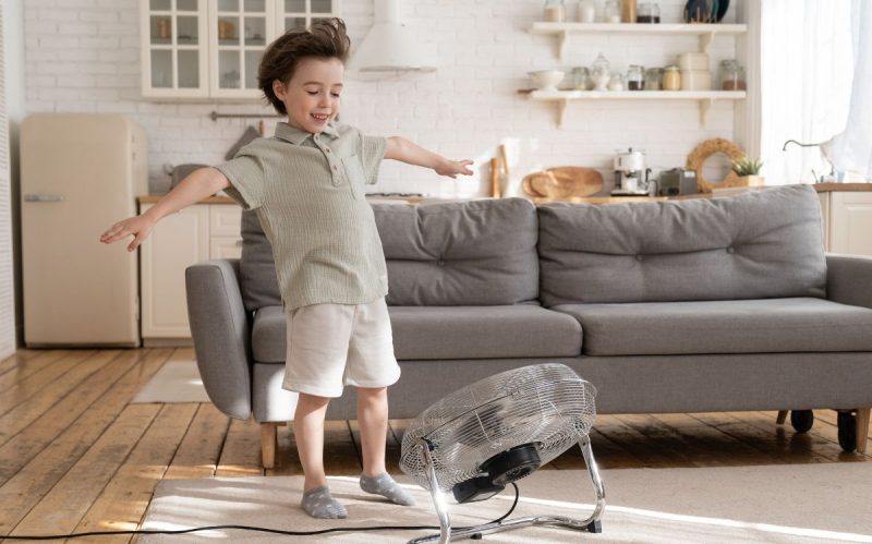 Niño refrescándose con el ventilador portátil 